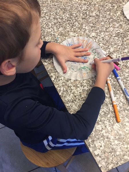 boy coloring on coffee filter with marker