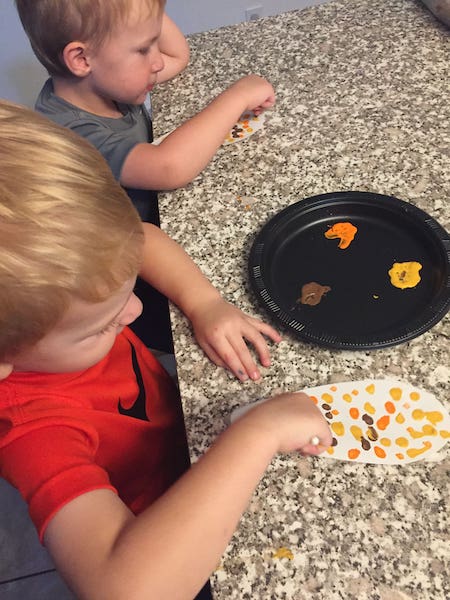 young kids painting paper with q tips