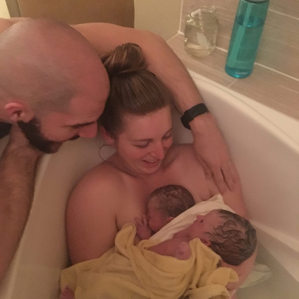 mom holding newborn twins in birthing tub twins in a birthing center