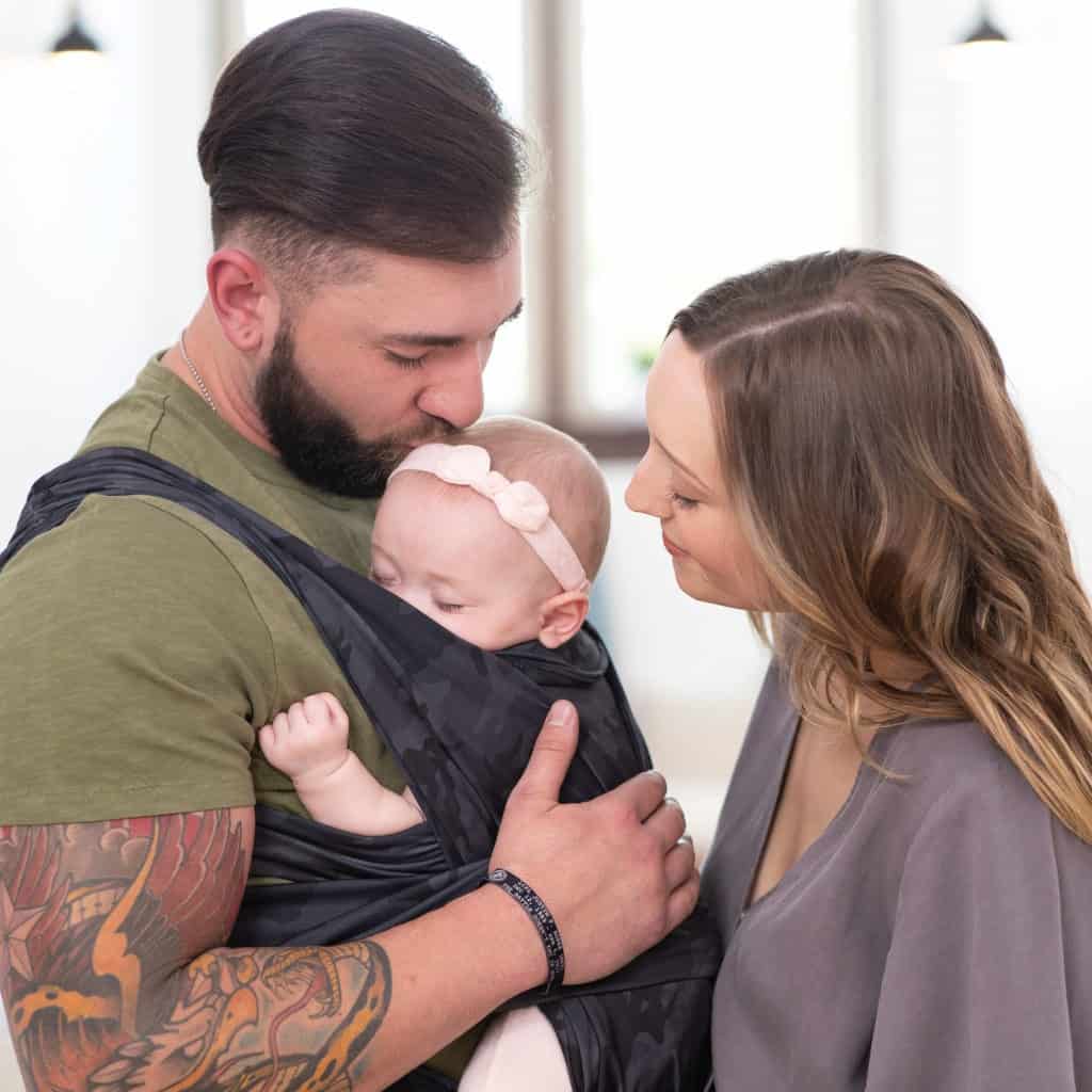 two parents looking at baby in a baby carrier