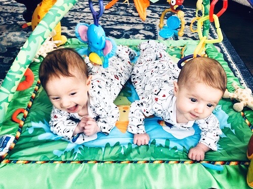twin babies doing tummy time on a floor mat container baby syndrome