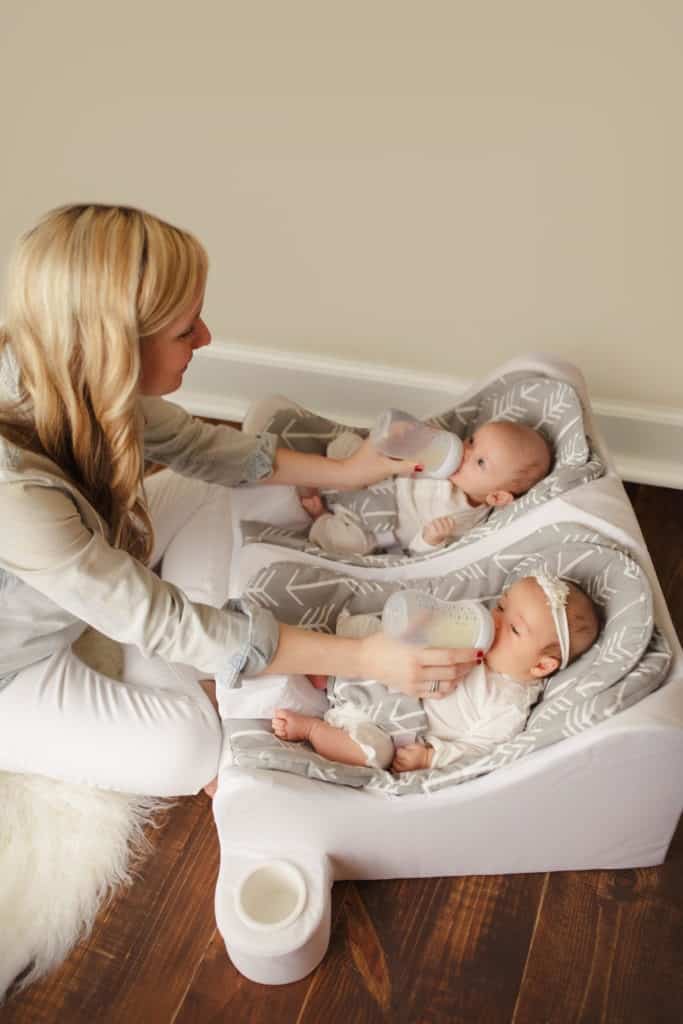 mom bottle feeding infant twins in table for two