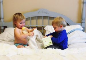 twins pulling out wipes from container on bed Keep Twins Busy