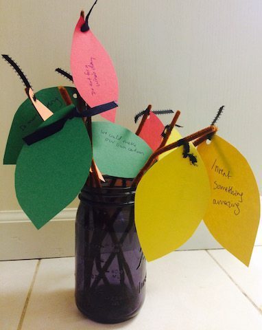 glass jar with paper leaves with written wishes New Year with Kids