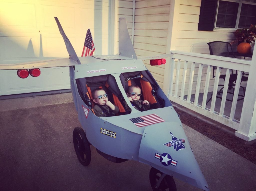 baby twin boys dressed as top gun characters in a stroller dressed up like an airplane