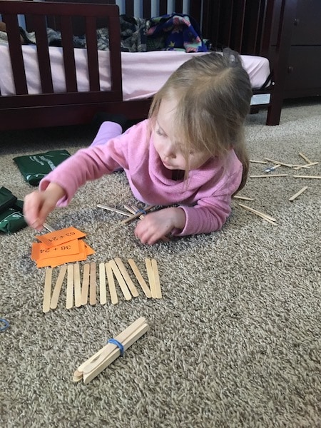 girl playing with popsicle sticks love of math