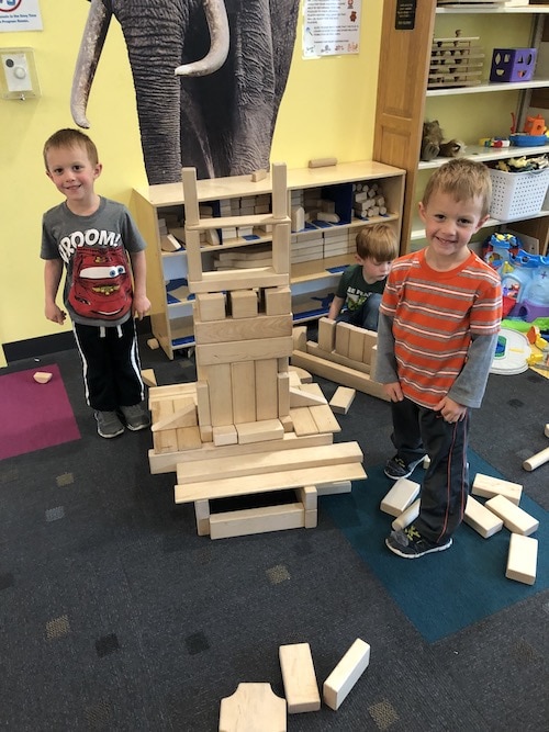 twin boys building with large wooden blocks choose toys