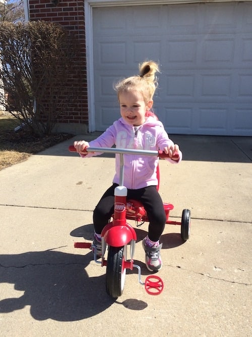 preschool girl on a tricycle choose toys