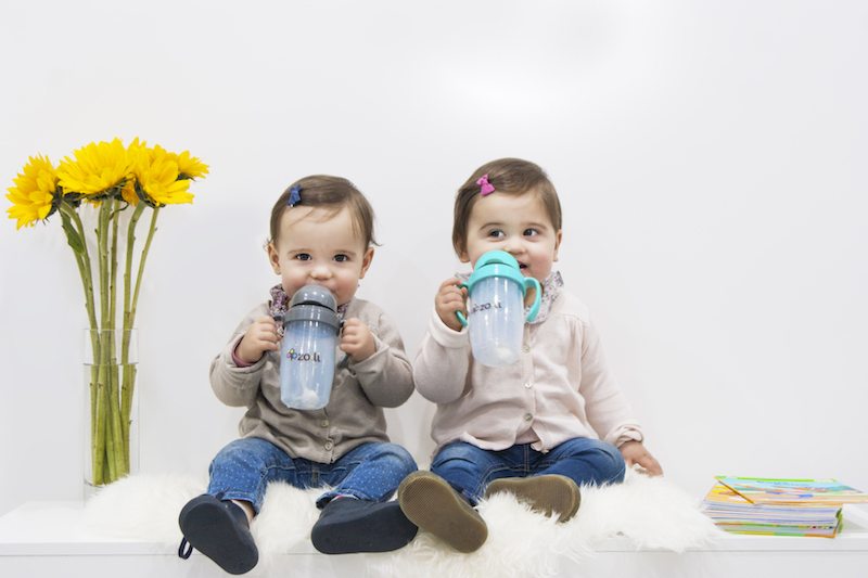 Twin Babies drinking out of bottles on rug
