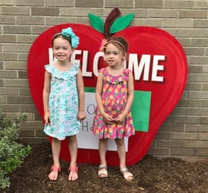 twin girls standing by school preparing twins for kindergarten