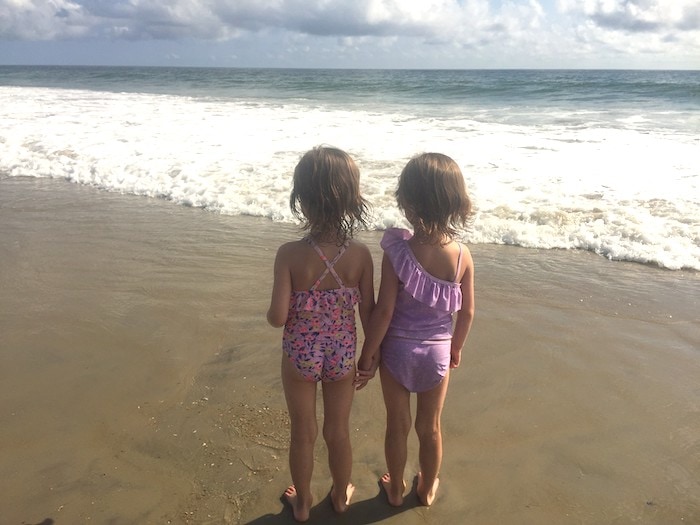 twin 5 year old girls on a beach embrace their individuality