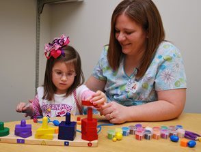 woman helping girl play with sensory toys at a table occupational therapy