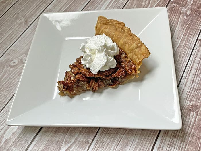 slice of pecan pie with whipped cream on a plate