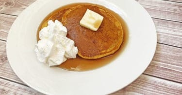 pumpkin pancakes with whipped cream butter and syrup on a plate
