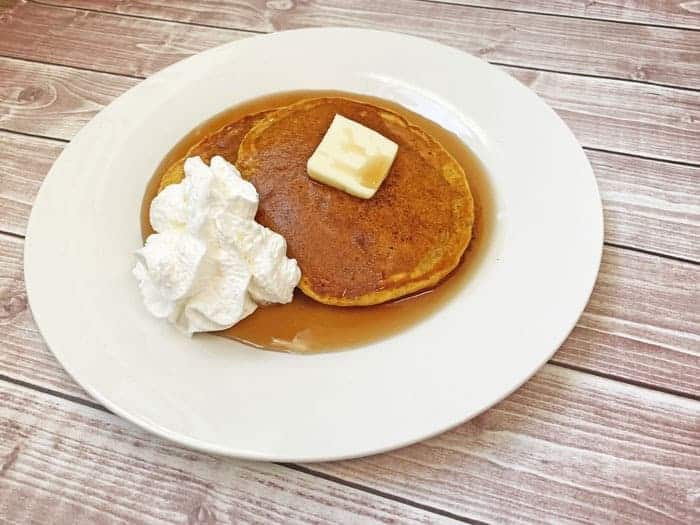 pumpkin pancakes with whipped cream butter and syrup on a plate