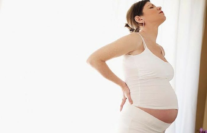 pregnant woman holding her back in discomfort twin pregnancy stories