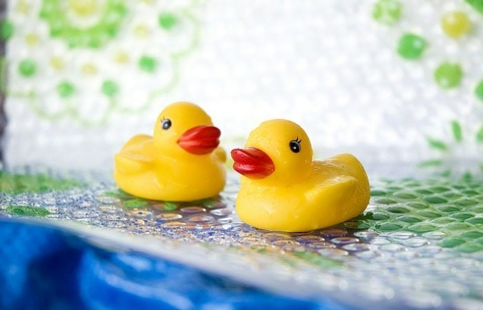 Two yellow rubber ducks on a green, blue, and white background.