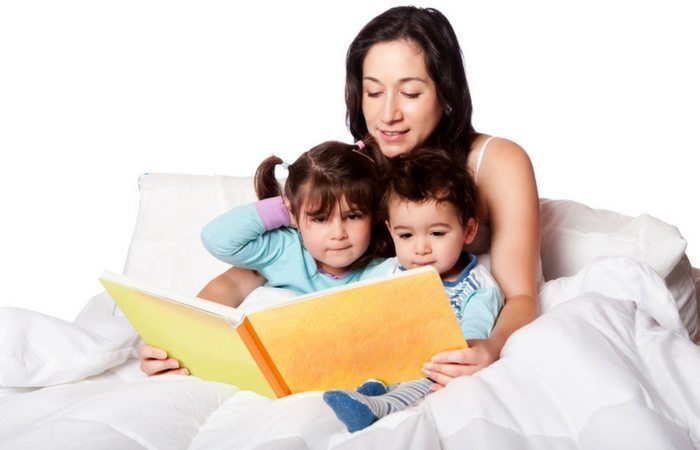 mom reading to kids in bed