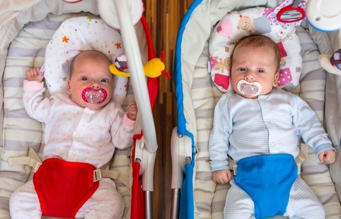 infant twins sittingin bouncy seats with pacifiers