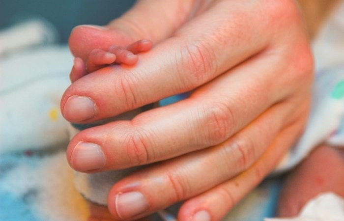 Adult holding newborn hand