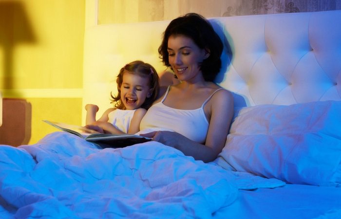 mom reading to daughter in bed