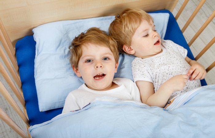 twin toddler boys in crib together