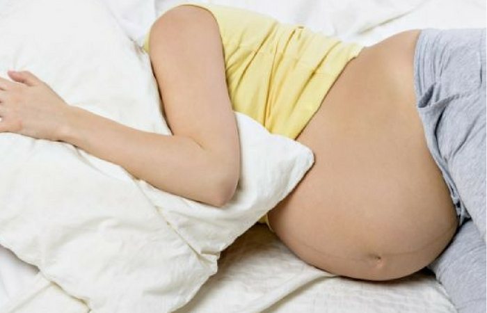 Pregnant woman laying on side in bed