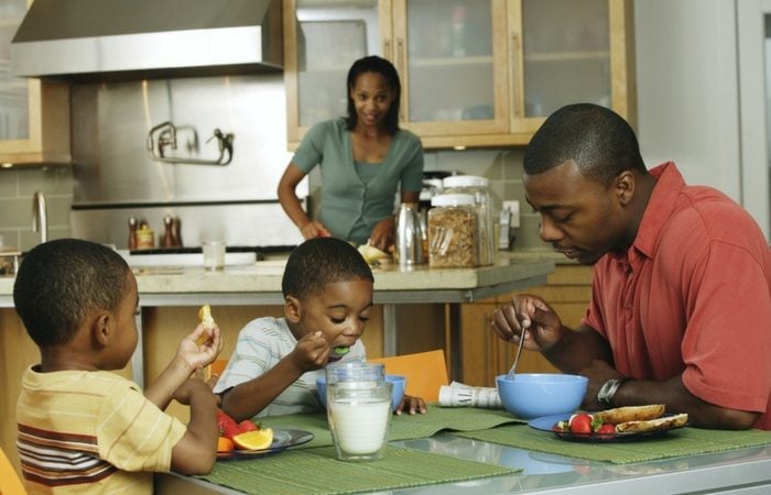 Family in kitchen with twin brothers eating breakfast