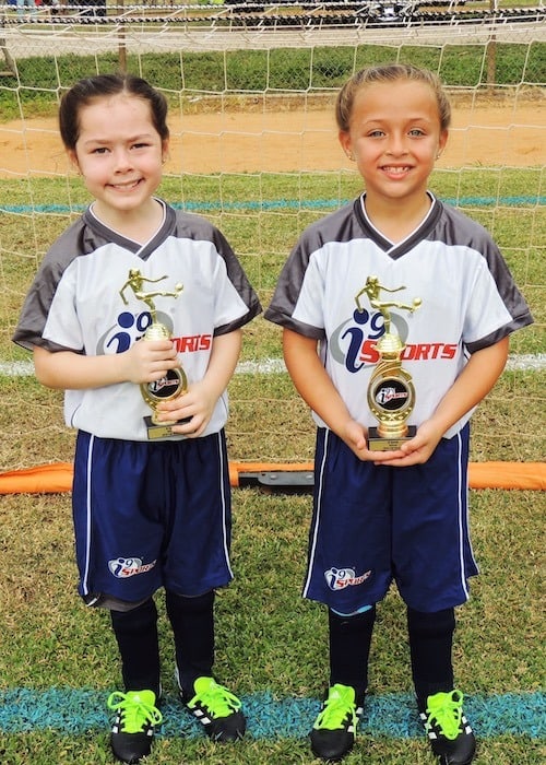 twin girls with soccer trophies after-school activities