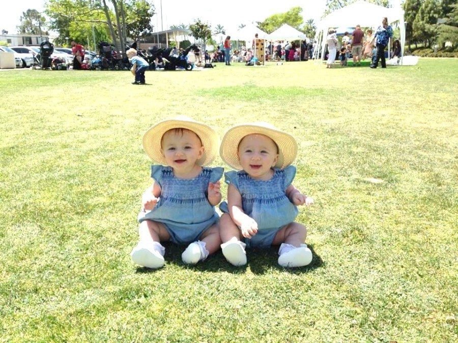 twin girl babies sitting on the grass out the door with twins