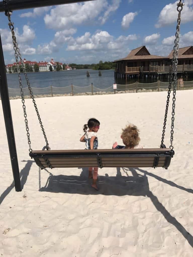 girls sitting on swing bench on the beach disney world with twins