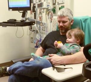 dad holding 1 year old boy waiting to get ear tubes surgery