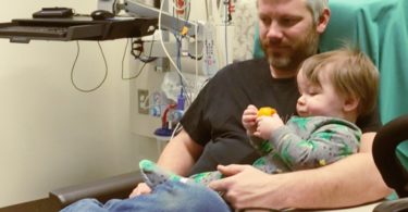 dad holding 1 year old boy waiting to get ear tubes surgery