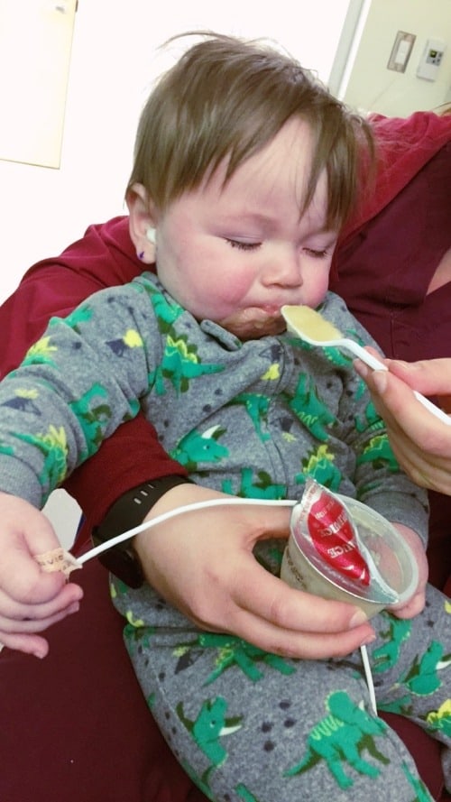 1 year old boy eating applesauce on parent's lap ear tubes