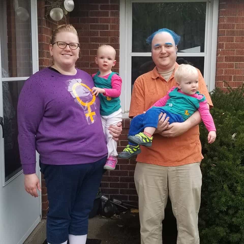 twin toddlers dressed as phil and lil from rugrats being held by their parents dressed as the rugrats parents