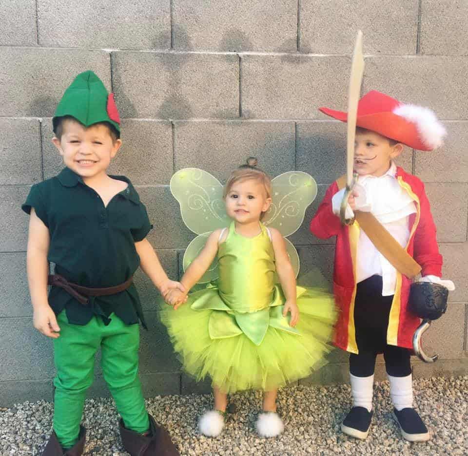 twin boys dressed as peter pan and captain hook with their younger sister dressed as tinkerbell in the middle