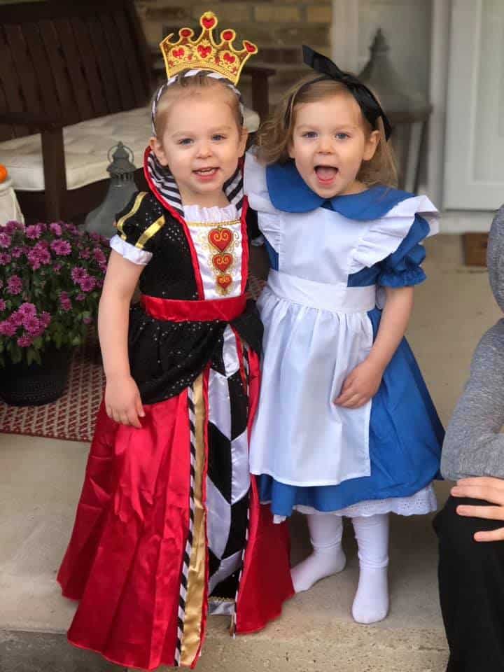 twin girls dressed up as alice and queen of hearts from alice in wonderland