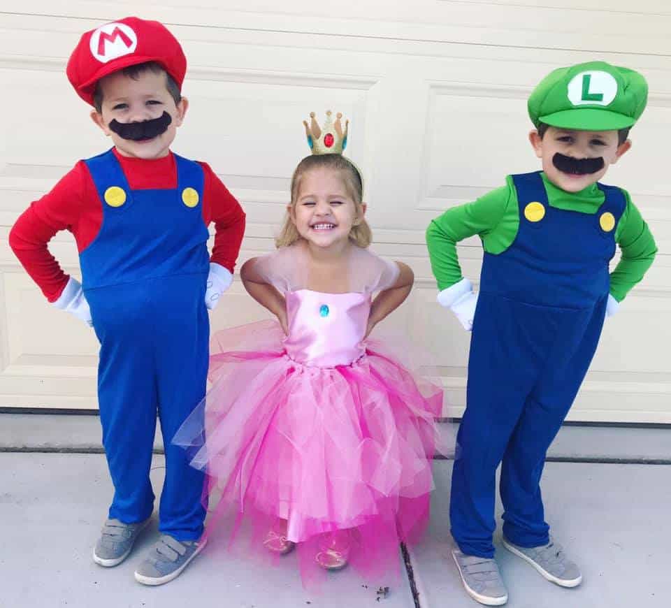 twin brothers dressed as mario and luigi and their sister in the middle dressed up as princess peach