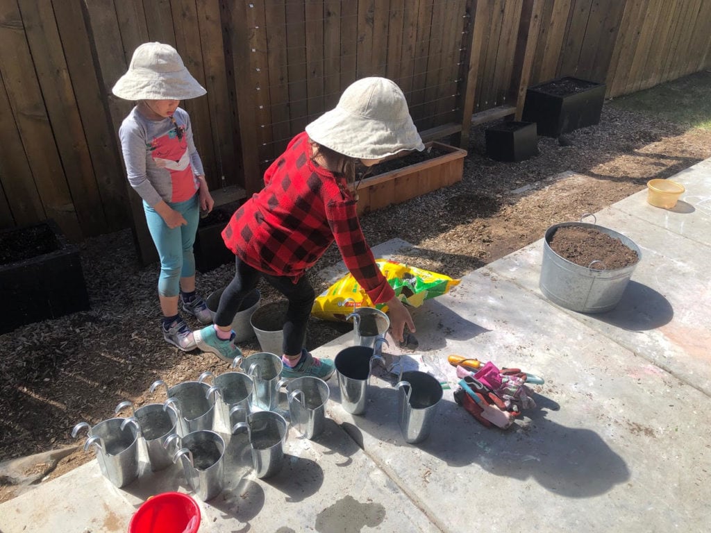 two girls playing with buckets and dirt not traveling