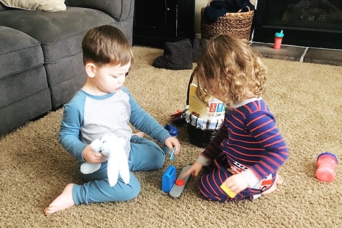 twin toddlers playing on carpet look forward