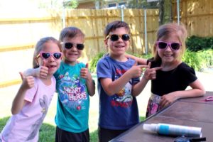 four kids wearing sunglasses summer shopping