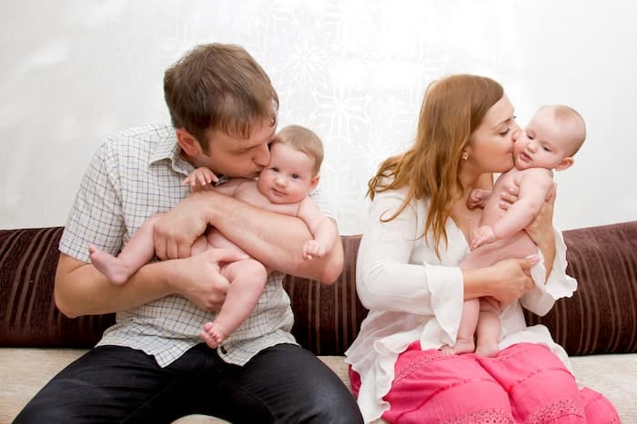 mom and dad kissing baby twins gift giving