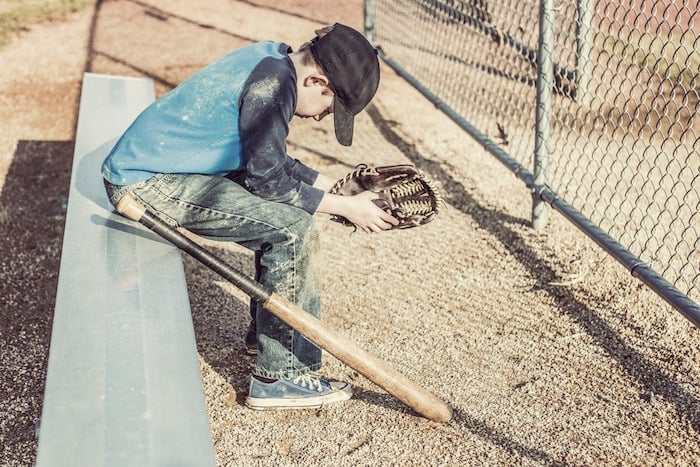 junior high school boy with baseball bat sitting on bench