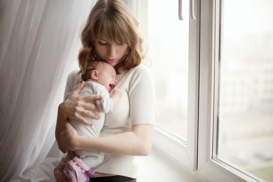 soothing mom holding newborn baby crying