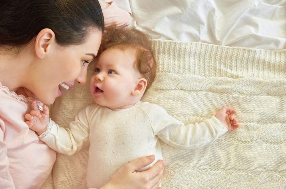 mom and baby laying on bed