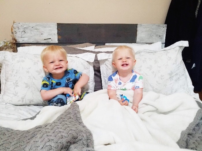 twin toddlers sitting in a big bed sleep regressions