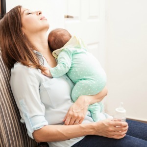 mom sleeping and holding baby sleep deprived