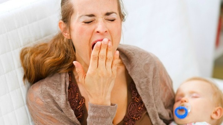 mother yawning holding sleeping baby sleep deprived