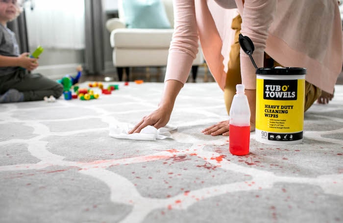 woman cleaning stain on rug after school messes