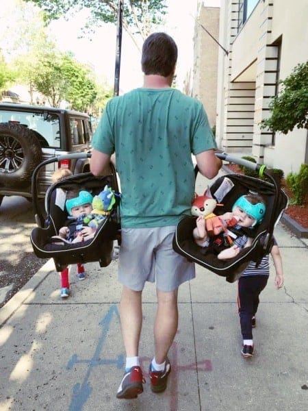 twin dads carrying car seats